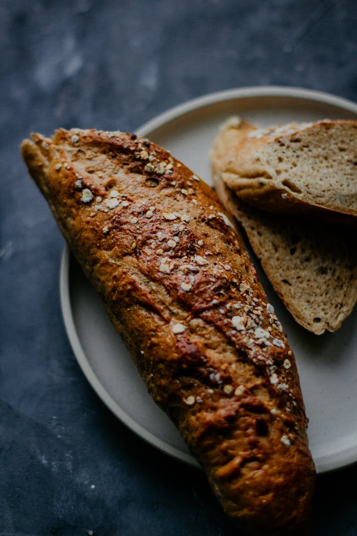 Close-up of homemade whole wheat bread with oats on a plate, dark background.