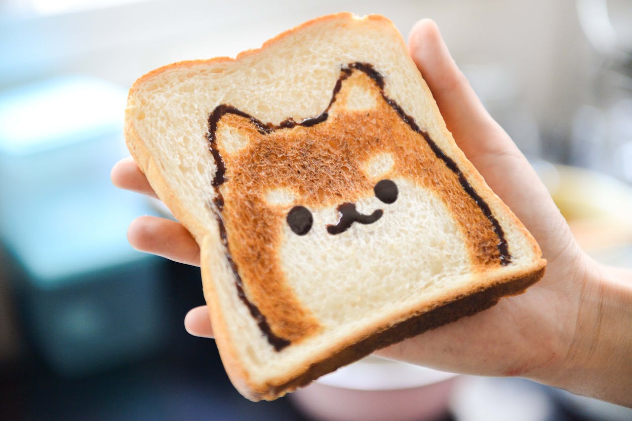 how-we-are Adorable Shiba Inu face toast art, perfect for breakfast fun, held by hand in a bright setting.